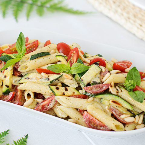 Penne con pesto di ricotta e basilico, zucchine, datterini e pinoli