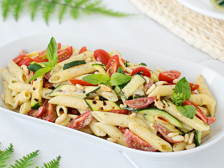 Penne con pesto di ricotta e basilico, zucchine, datterini e pinoli